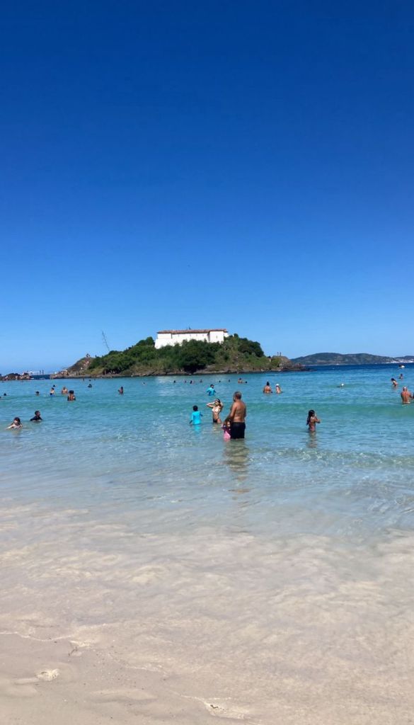 Praia do Forte em Cabo Frio com turistas nadando e Ilha do Japonês ao fundo
