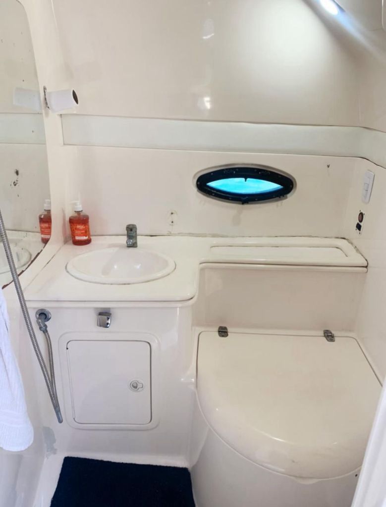 Banheiro completo da lancha com pia, espelho e janela