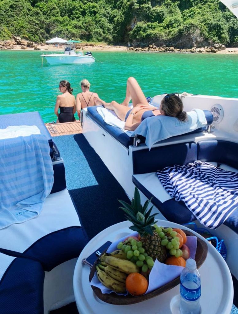 Turistas relaxando na proa da lancha com frutas e bebidas em Búzios