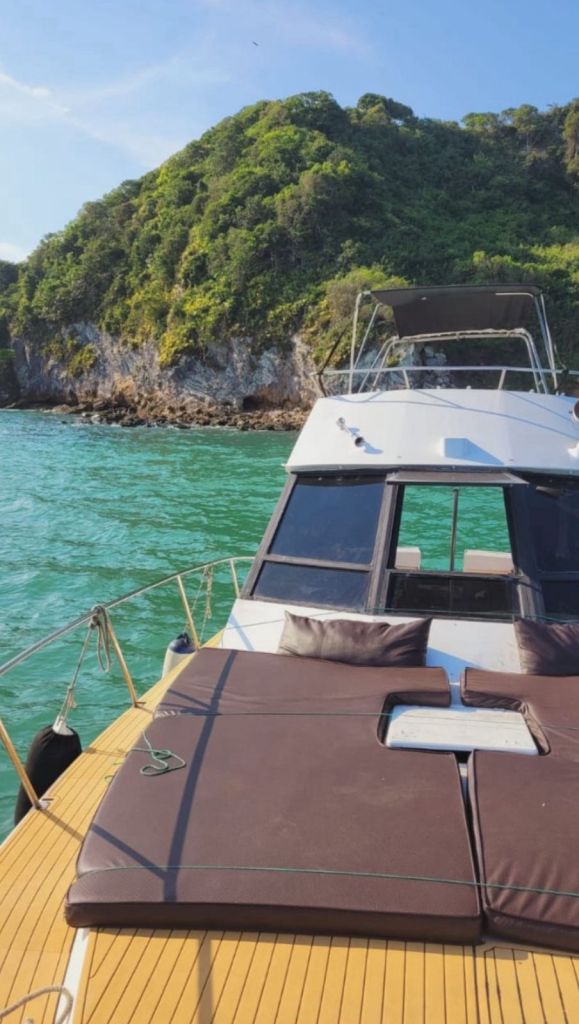 Vista da proa da lancha com almofadas e mar verde ao fundo