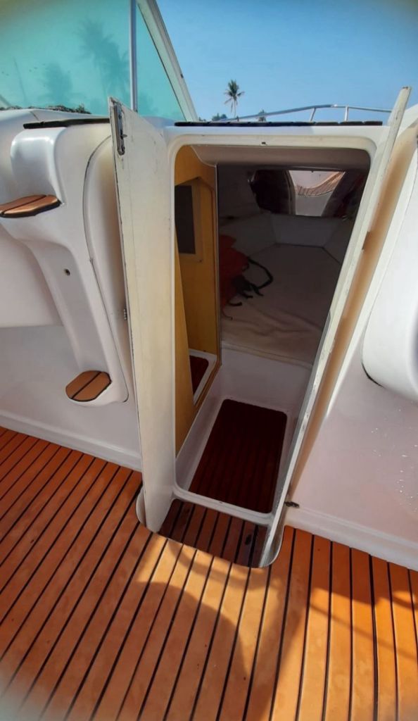 Entrada da cabine da lancha com piso de madeira e porta