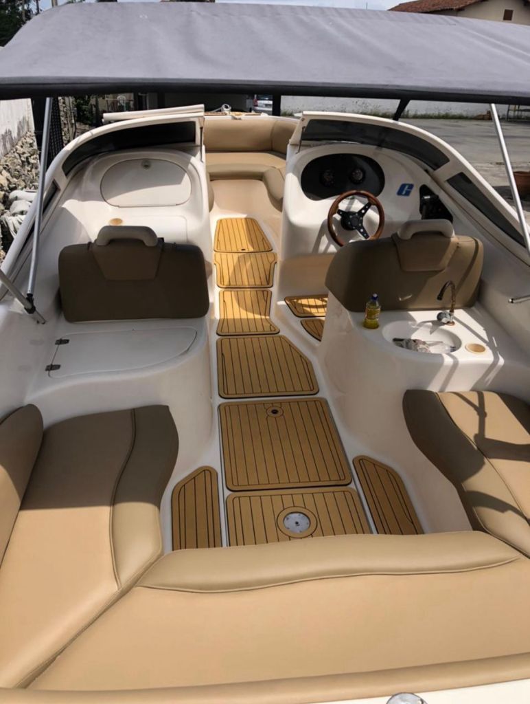 Visão geral do interior da lancha com estofamento bege e piso de madeira