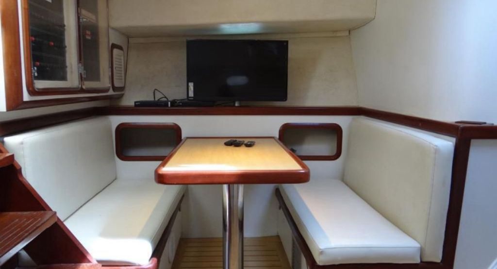 Área de refeições interna da lancha 45 pés com mesa e estofado