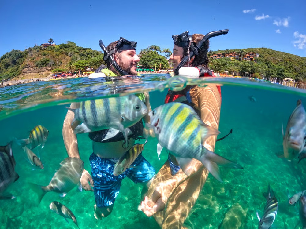 Passageiros com mascara de snorkel praticando mergulho durante passeio de escuna em Búzios