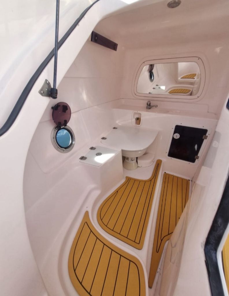 Banheiro compacto com acabamento branco a bordo da lancha